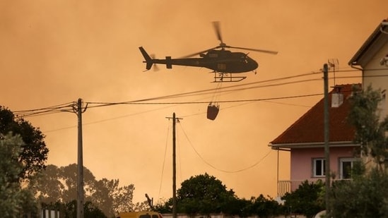 A fire fighting helicopter works to contain a wildfire in Leiria, Portugal.&nbsp;(Reuters)