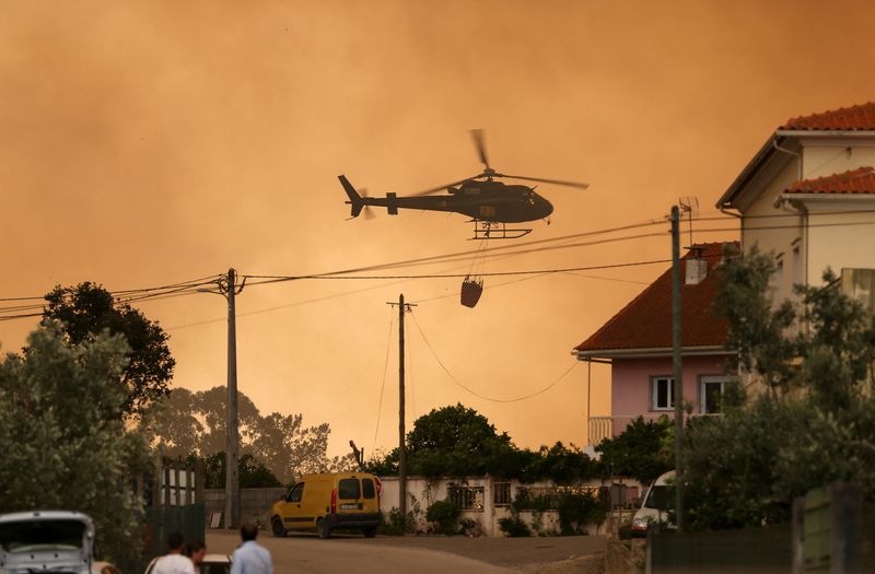 A fire fighting helicopter works to contain a wildfire in Leiria, Portugal.&nbsp; (Reuters)