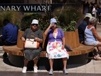 Women rest on a bench and drink water in hot weather during lunch hour in the financial district of Canary Wharf in London, Britain.
