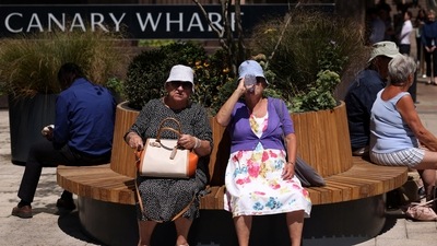 Women rest on a bench and drink water in hot weather during lunch hour in the financial district of Canary Wharf in London, Britain. (REUTERS)