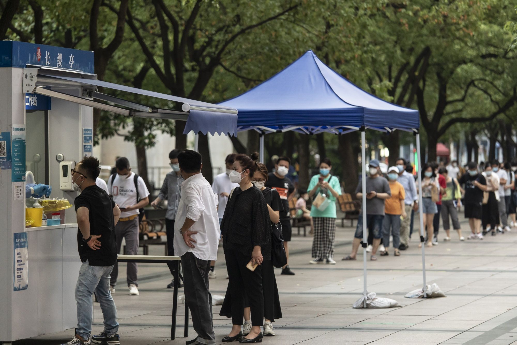 Office workers line up at a Covid testing booth in downtown Shanghai. (Bloomberg) Office workers line up at a Covid testing booth in downtown Shanghai. (Bloomberg)
