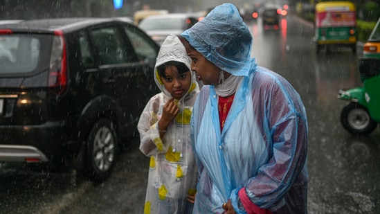A woman with her ward amid monsoon rains in New Delhi on Saturday.(PTI)