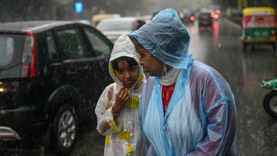 A woman with her ward amid monsoon rains in New Delhi on Saturday. (PTI)