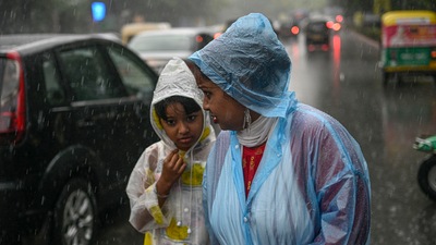 A woman with her ward amid monsoon rains in New Delhi. (PTI)