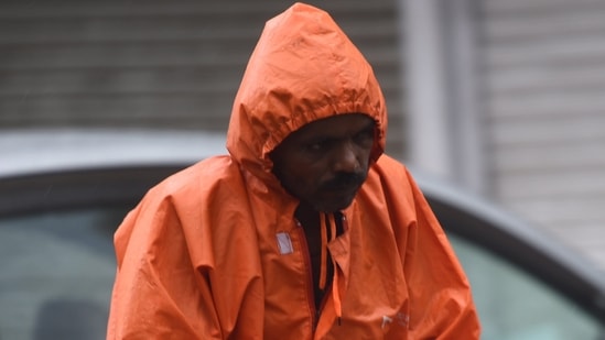 A man wearing a raincoat rides a bicycle during monsoon rain.(PTI)
