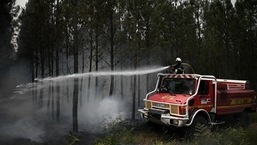 Um bombeiro pulveriza água enquanto a fumaça sobe de um incêndio florestal perto de Louchats, enquanto os incêndios florestais continuam a se espalhar na região de Gironde, no sudoeste da França.