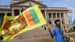 Um homem usa uma faixa na cabeça com um slogan contra o presidente interino do Sri Lanka, Ranil Wickremesinghe, enquanto agita a bandeira nacional do Sri Lanka perto do secretariado presidencial em Colombo, no domingo.
