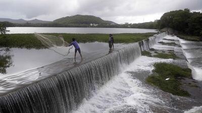 Man throws net to catch fish as Pashan lake overflows due to incessant rains. Pune sees highest day temperature at 30 degrees Celsius (July 3 and July 4) making it the coolest maximum temperature recorded since 2012. (RAHUL RAUT/HT)
