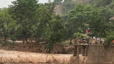A vehicle is seen near a part of a bridge that was washed away by flood waters along a river in Qingyang in northwest China's Gansu province Saturday, July 16, 2022. (AP)