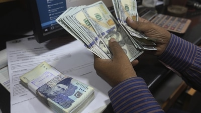 A Pakistani money trader counts US dollars for a customer at a currency exchange office, in Karachi, Pakistan. (AP)