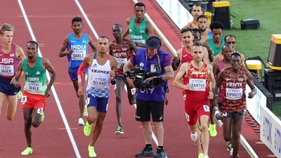 Athletes in the men's 3000m steeplechase final run around a cameraman on the track on Day 4 of the World Athletics Championships (AFP)