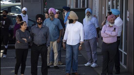 People gather at the scene as police investigate a fatal shooting in Surrey, British Columbia, Canada, on Thursday. Ripudaman Singh Malik, the man acquitted in the 1985 Air India terrorist bombing, was killed in the shooting, according to several media outlets. (AP)