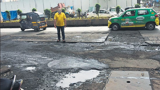 Dhaval Shah, a Lokhandwala resident, points to potholes near DN Nagar Metro station HT Photo