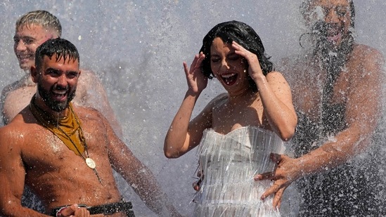 Members of the 'Australian cabaret and Circus troupe' cool down in a fountain on the Southbank in London on Tuesday.(AP)
