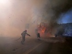 A firefighter tries to extinguish the flames next to motorcycles during a wildfire near Megara town, west of Athens, Greece.(PTI) A firefighter tries to extinguish the flames next to motorcycles during a wildfire near Megara town, west of Athens, Greece.(PTI)
