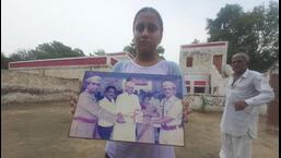 A family member of slain DSP Surender Singh holds his picture in their home village of Hisar on Wednesday.  The DSP's younger brother demanded either a CBI or a judicial inquiry into his murder.  (Photo HT)