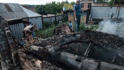 Moradores locais ajudam bombeiros a apagar um incêndio no quintal de uma casa na cidade de Bakhmut após um ataque aéreo na Ucrânia. 