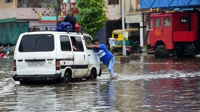 A driver of a van carrying school children, pushes the vehicle across a flooded street after heavy rains in Ahmedabad. (Photo by AFP) A driver of a van carrying school children, pushes the vehicle across a flooded street after heavy rains in Ahmedabad. (Photo by AFP)