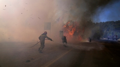A firefighter tries to extinguish the flames next to motorcycles during a wildfire near Megara town, west of Athens, Greece. (PTI) A firefighter tries to extinguish the flames next to motorcycles during a wildfire near Megara town, west of Athens, Greece. (PTI)