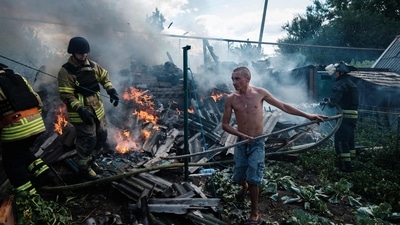 A local resident helps firefighters to put out a fire in a yard of a house in the town of Bakhmut following an airstrike. (AFP)