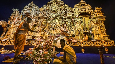 A Hindu priest performs rituals before the idol of Goddess Durga at a community pandal, in Kolkata. Officials of community committees organising big-budget Durga Puja pandals in the city are in hope that Covid situation would not deteriorate so that they can make the entrance more accessible. &nbsp; (PTI Photo/Swapan Mahapatra)
