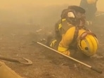 Firefighters crouch on the ground as smoke rises during a wildfire in Parque Natural O Invernadeiro, Spain July 21, 2022 in this still image obtained from a social media video. Twitter/@BrifLaza/via REUTERS