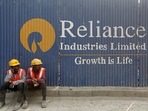 Labourers rest in front of an advertisement of Reliance Industries Limited at a construction site in Mumbai.