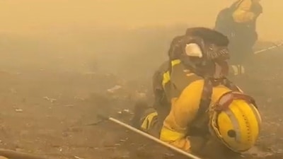 Firefighters crouch on the ground as smoke rises during a wildfire in Parque Natural O Invernadeiro, Spain July 21, 2022 in this still image obtained from a social media video. Twitter/@BrifLaza/via REUTERS (TWITTER/@BRIFLAZA via REUTERS)