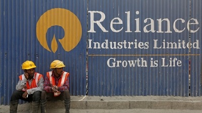 Labourers rest in front of an advertisement of Reliance Industries Limited at a construction site in Mumbai. (REUTERS)