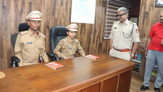 Two 13 year old boys, Mitilesh and Mohammad Salman, sit at the DCP's desk in his chambers in Bengaluru on Thursday and get a feel of their dream job. (Image source: CK Baba/Twitter)