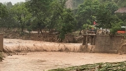 Um veículo é visto perto de uma parte de uma ponte que foi levada pelas águas das enchentes ao longo de um rio em Qingyang, na província de Gansu, noroeste da China.