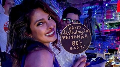 Priyanka Chopra, who is an '80's' baby, held a huge cake pop with "Happy birthday Priyanka 80's baby" written on it struck a cute pose for the camera with Nick Jonas in the background. (Instagram/@parineetichopra) Priyanka Chopra, who is an '80's' baby, held a huge cake pop with "Happy birthday Priyanka 80's baby" written on it struck a cute pose for the camera with Nick Jonas in the background. (Instagram/@parineetichopra)