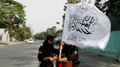 Taliban fighters install a Taliban flag on a checkpoint in Kabul, Afghanistan. (Reuters)