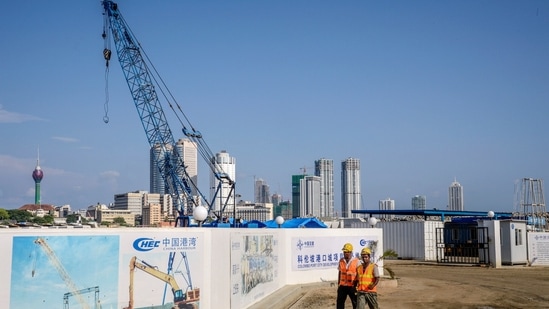Workers pass hoardings for the Colombo Port City, developed by China Harbour Engineering Co., a unit of China Communications Construction Co in Colombo, Sri Lanka, in 2018. Photographer: Atul Loke/Bloomberg.