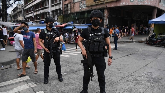 Members of police Special Weapons and Tactics (SWAT) stand guard along a popular market street in Manila.(AFP)