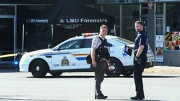 Police officers stand near a crime scene after authorities alerted residents of multiple shootings targeting transient victims in the Vancouver suburb of Langley, British Columbia, Canada.