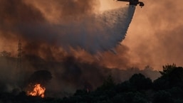 A firefighting helicopter makes a water drop as a wildfire burns at the village of Krestena, in the western Peloponnese, Greece.