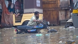 A man pushes his motorbike through a flooded street after heavy monsoon rainfall in Karachi. 