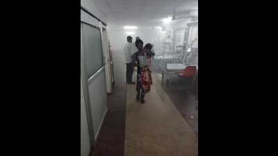 A patient’s attendant rushing out with the sick child out of the ward filled with smoke at SN Children’s Hospital on Sunday night. (HT PHOTO)