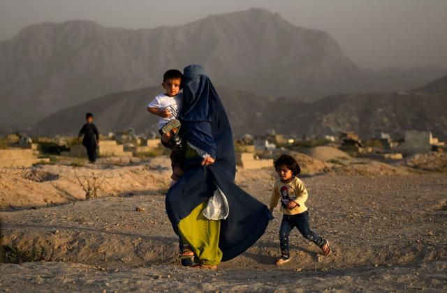 Walking past a cemetery in Kabul on July 19, 2022. (AFP) Walking past a cemetery in Kabul on July 19, 2022. (AFP)