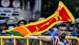 Um manifestante agita uma bandeira do Sri Lanka perto de barricadas policiais durante uma marcha de protesto em direção ao escritório da Secretaria Presidencial em Colombo.