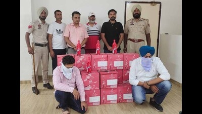 The accused and the illicit liquor seized from them in Ludhiana police custody on Thursday. (HT)