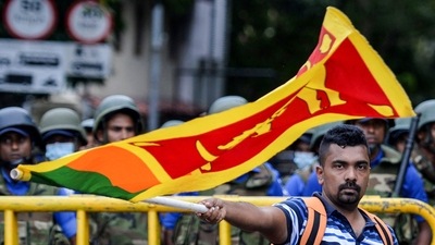 A demonstrator waves a Sri Lankan flag near police barriacdes during a protest march towards the Presidential secretariat office in Colombo. (AFP) A demonstrator waves a Sri Lankan flag near police barriacdes during a protest march towards the Presidential secretariat office in Colombo. (AFP)