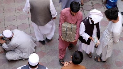 An Afghan money exchange dealer carries bundles of banknotes at an exchange market, following banks and markets reopening after the Taliban took over in Kabul, Afghanistan.&nbsp; (REUTERS)