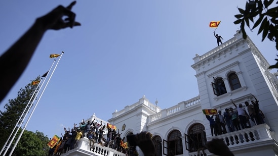 A Sri Lankan protester waves the national flag from the roof top of Sri Lankan Prime Minister Ranil Wickremesinghe's office. (AP Photo)