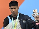 Indian weightlifter Sanket Sargar atop the podium poses after winning the silver medal in the men's 55kg category weightlifting event(PTI)
