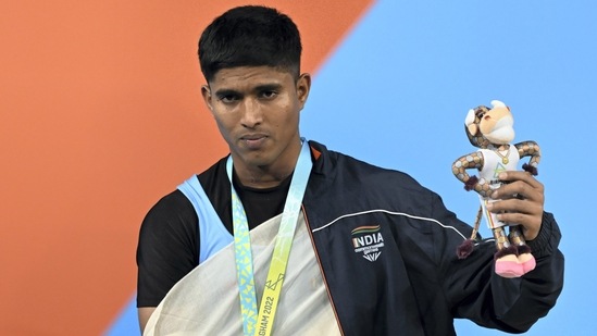 Indian weightlifter Sanket Sargar atop the podium poses after winning the silver medal in the men's 55kg category weightlifting event(PTI)