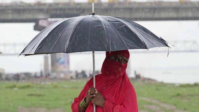 A woman walks with an umbrella in the rain by the banks of the Ganga in Prayagraj. (AP PHOTO)