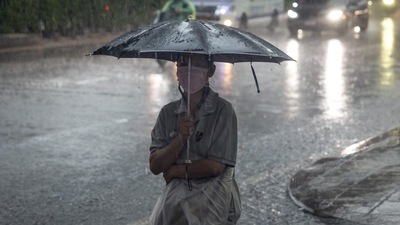 A woman protects herself with an umbrella as she walks down the street during heavy rain. (Representational image) (AFP) A woman protects herself with an umbrella as she walks down the street during heavy rain. (Representational image) (AFP)