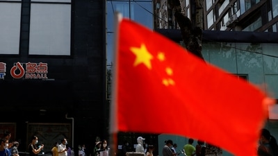 A China's flag flutters near people lining up to get tested at a makeshift nucleic acid testing site. (File image) (REUTERS)